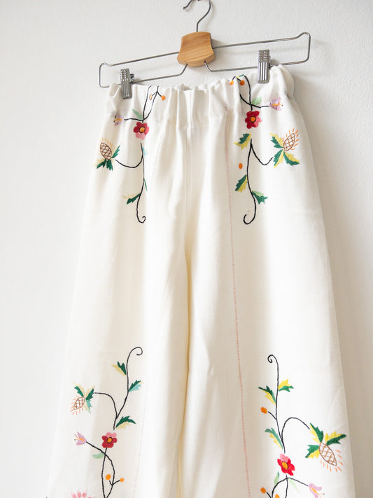 Pantalón blanco con bordado rosa.