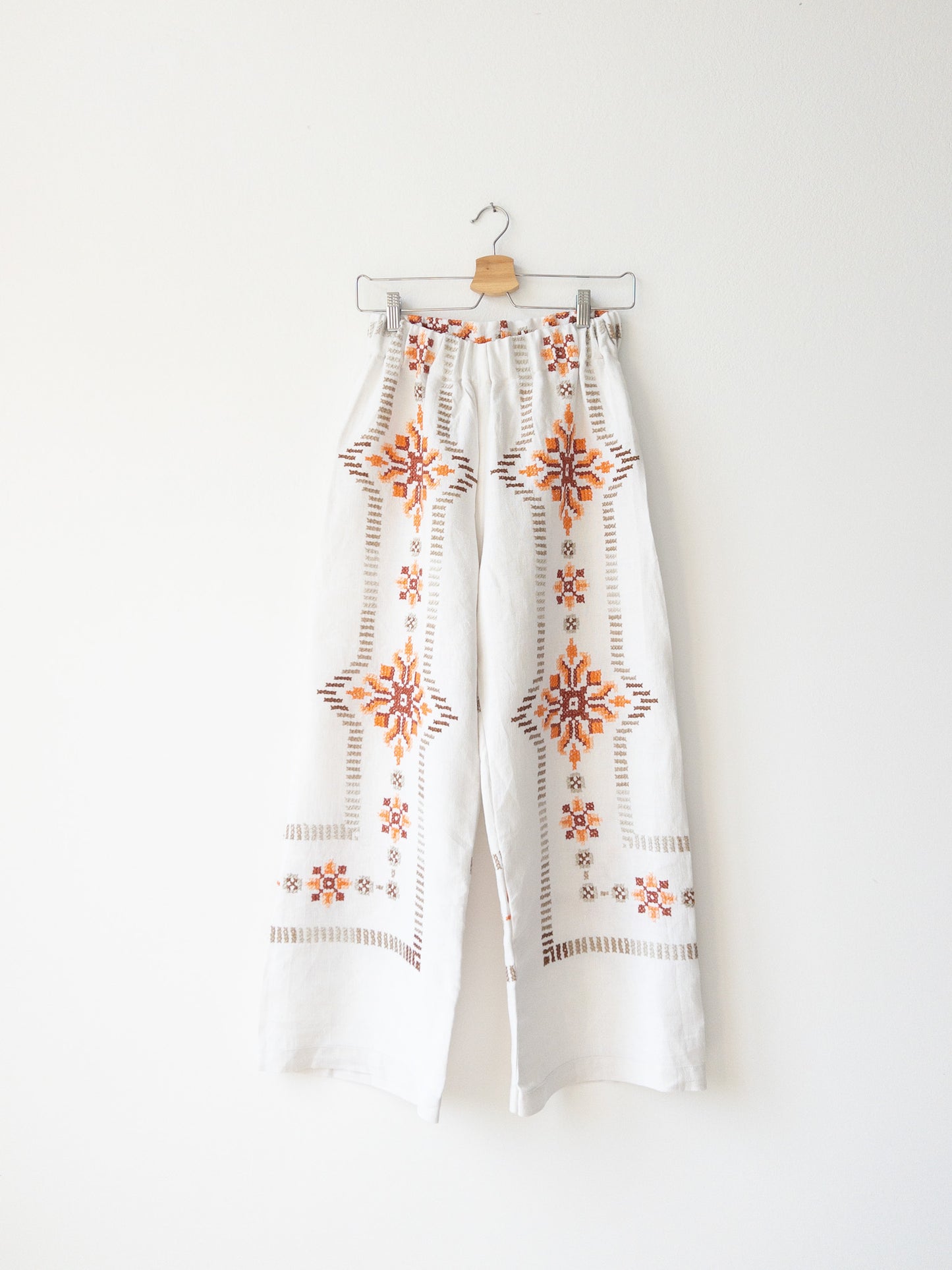 Pantalón blanco con bordado rosa.